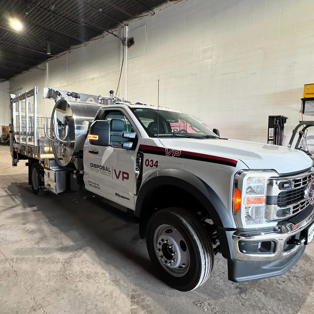 A white VP Disposal porta potty service and delivery truck parked in the shop