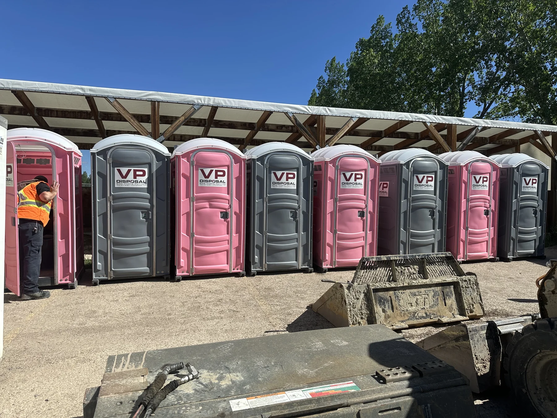 Pink and grey VP Disposal porta potties lined up in the yard