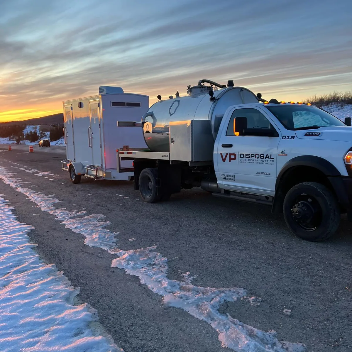 A VP Disposal truck towing a washroom trailer down a highway at sunrise
